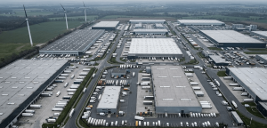 Aerial view of commercial wind turbines installed near an industrial park with warehouses and logistics facilities
