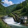 Small hydropower station on a mountain stream with dam, penstock pipe, and power house